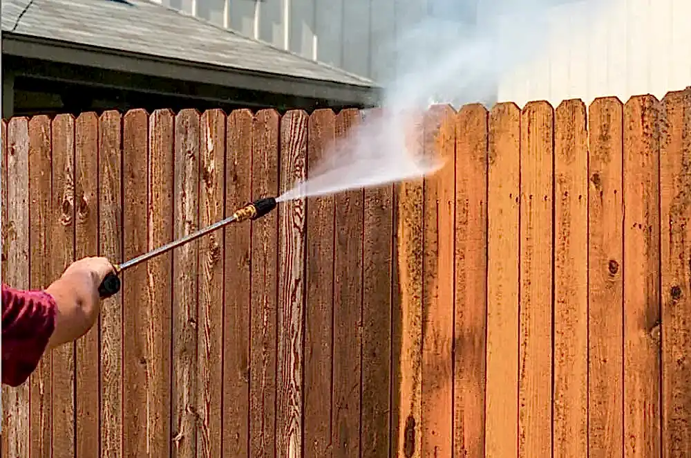 a fence being power washed